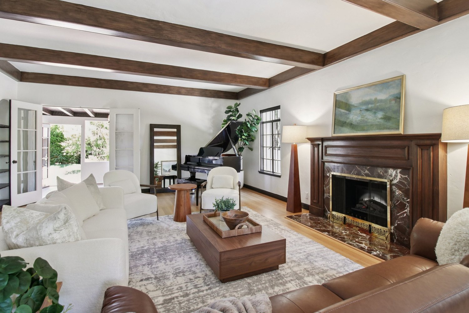 The staged living room at 1560 University Avenue — beamed ceiling, a marble fireplace and a grand piano beyond